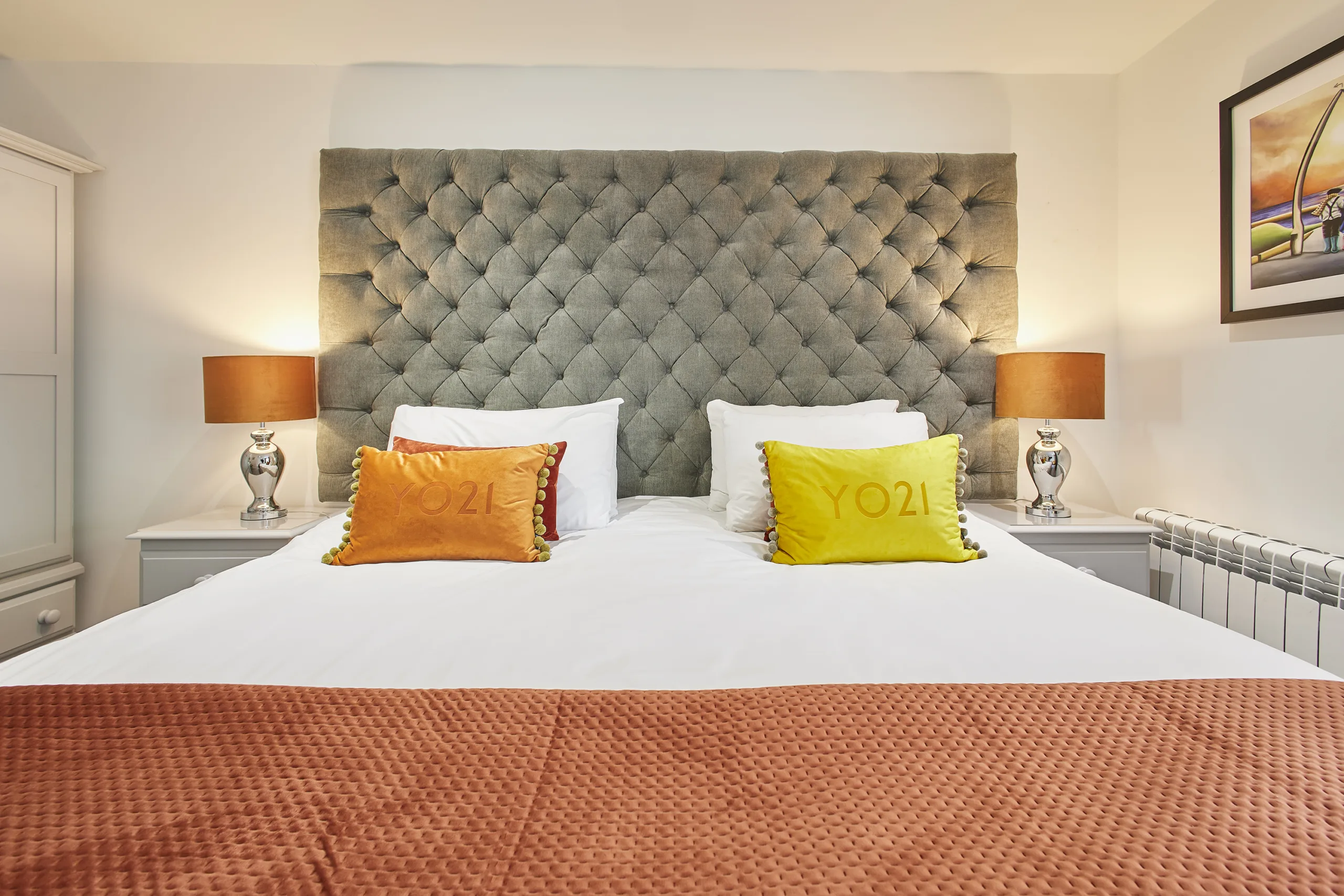 first bedroom boasts a luxurious super-king size bed dressed in crisp white linen, complemented by a calming blue colour scheme and a flat-screen TV