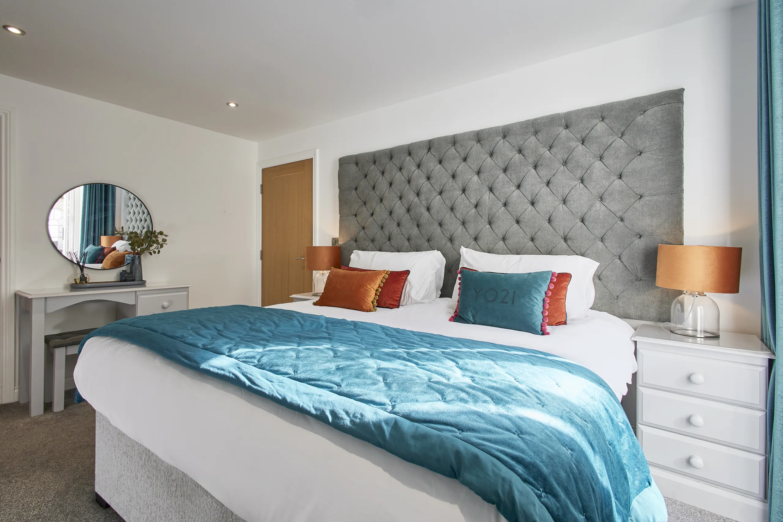 first bedroom boasts a luxurious super-king size bed dressed in crisp white linen, complemented by a calming blue colour scheme and a flat-screen TV